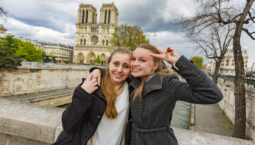 Gay women couple with the Notre Dame Cathedral while on a romantic vacation or honeymoon in Paris, France