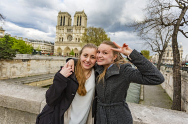 Gay women couple with the Notre Dame Cathedral while on a romantic vacation or honeymoon in Paris, France